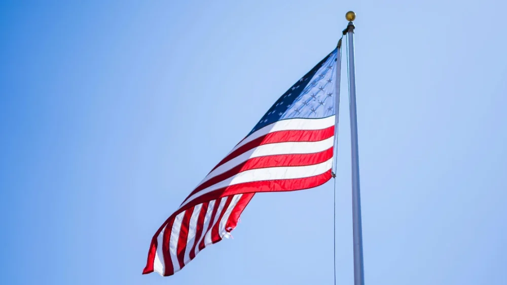 American flag flying against a clear blue sky, symbolizing U.S. military service and veteran legacy